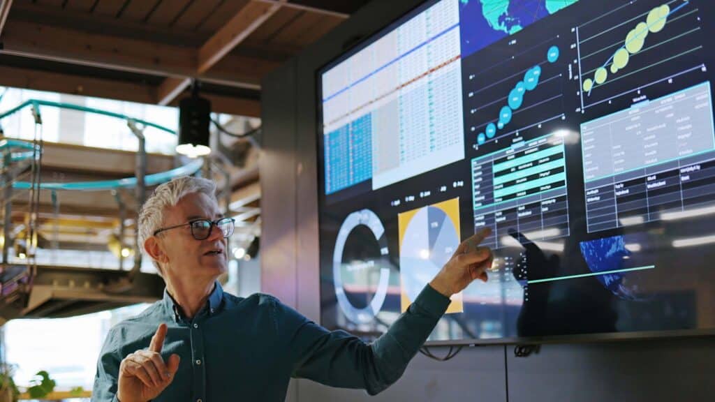 Man presenting data on a large screen in a Technology-Assisted Review (TAR) Consulting session.