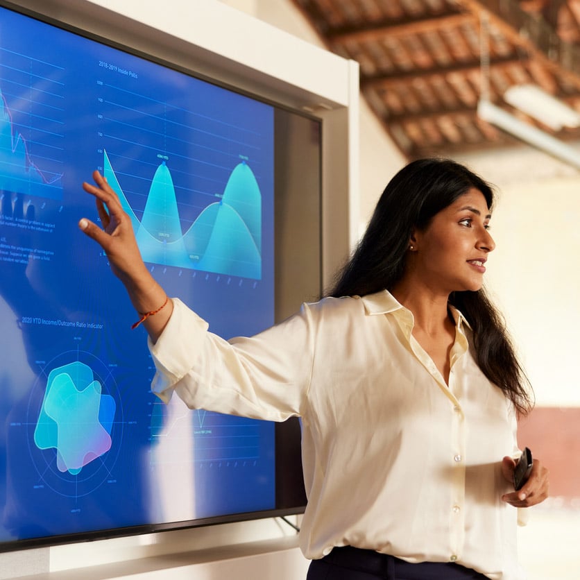 Woman presenting data charts on a large screen during an organizational strategy consulting session.