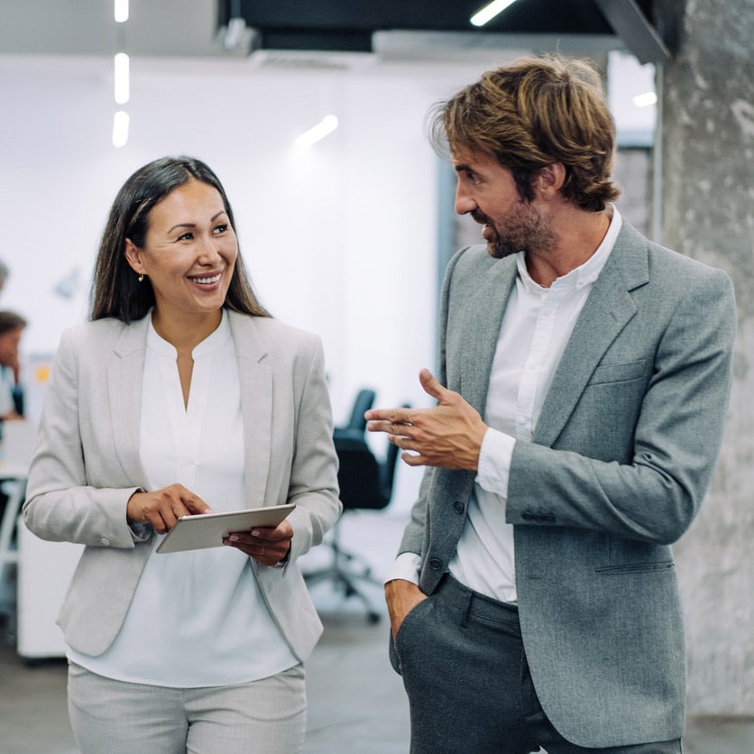 Two professionals in suits discuss workforce development consulting in a modern office.