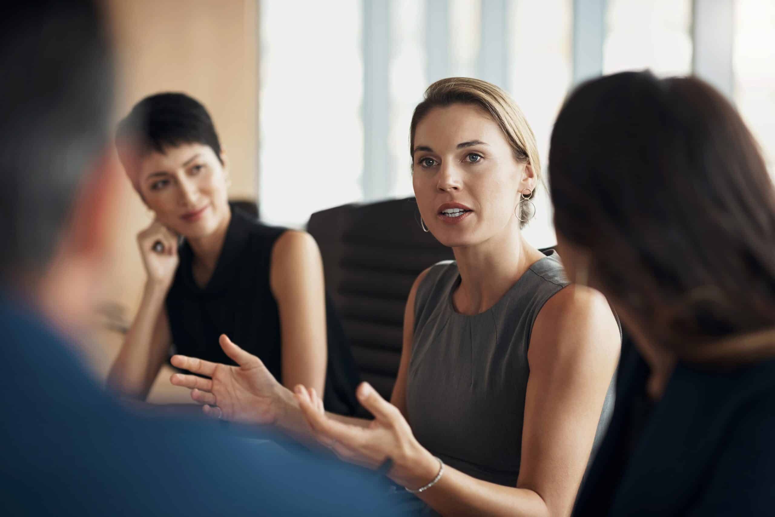 Woman speaking in a meeting on Litigation Consulting Services as others listen attentively.