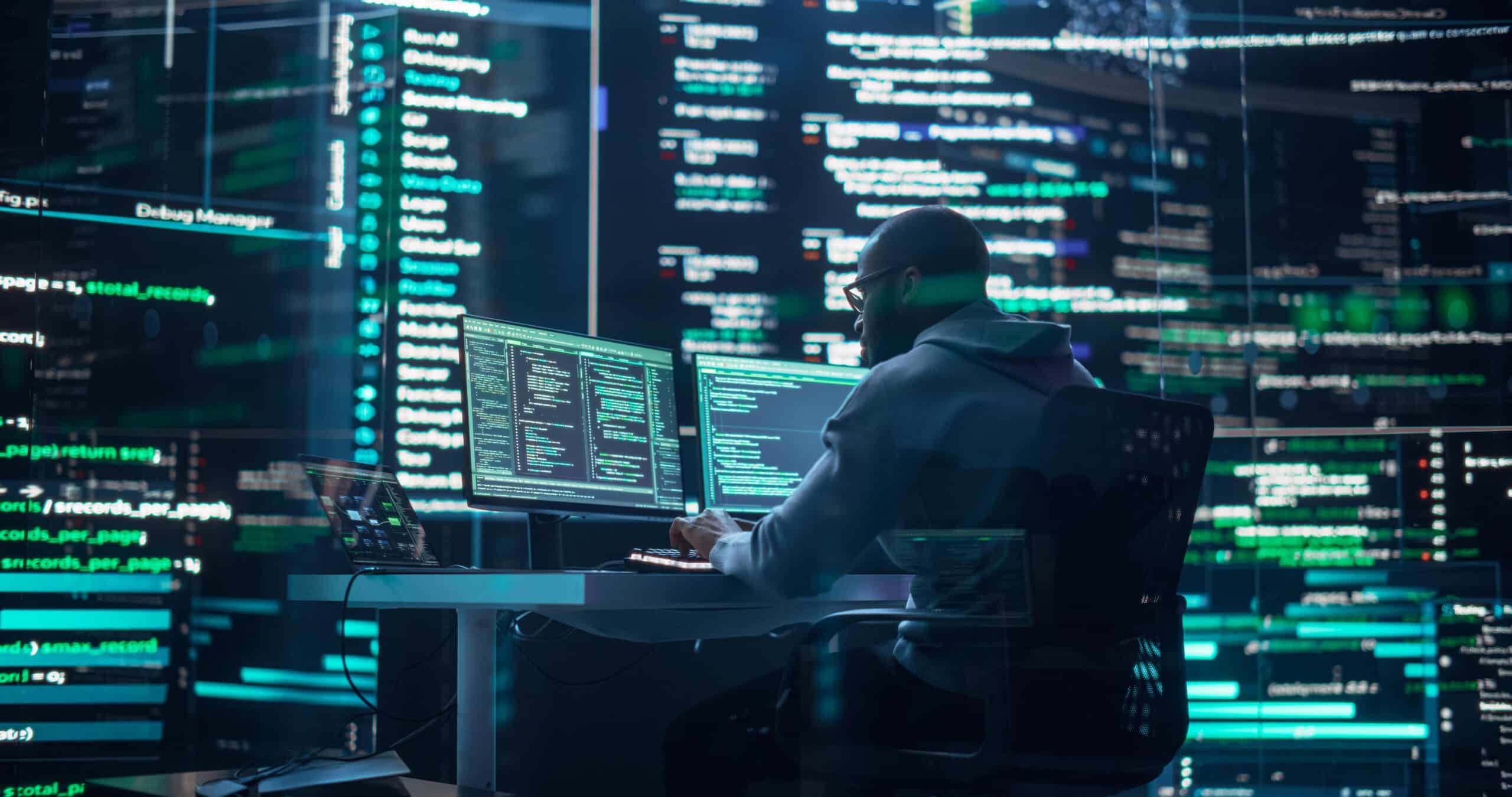 A person coding at a desk with multiple monitors, focused on Law Firm IT Consulting solutions.