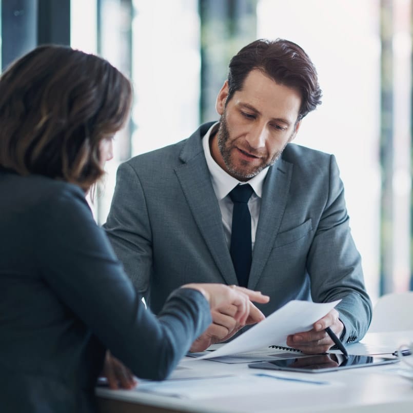 Two Economic Damages Consultants in business attire review documents together at an office table.