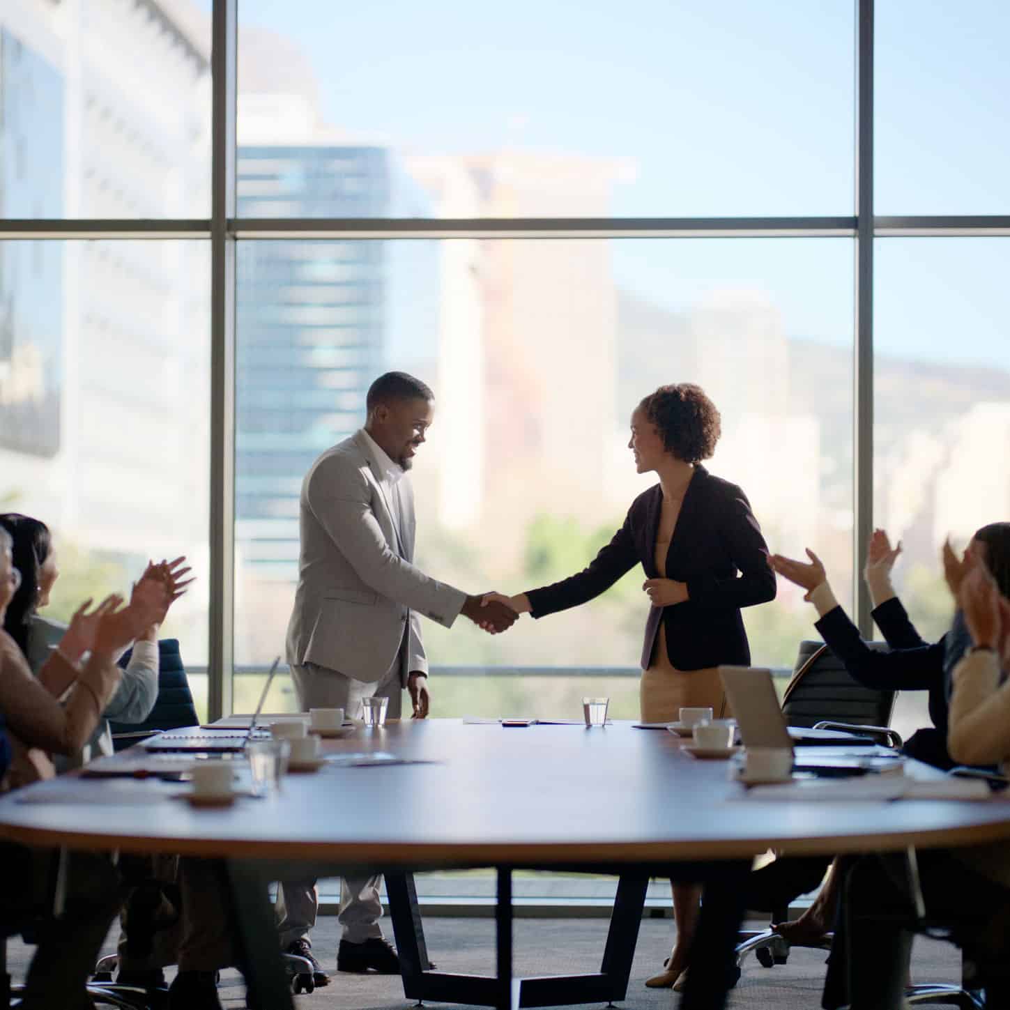 Two professionals shaking hands in meeting room after a successful M&A Strategy Consulting session.