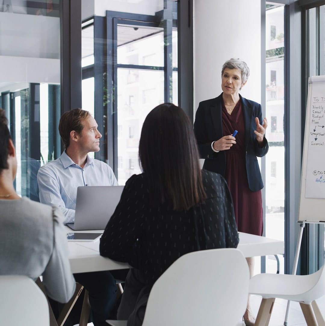 A woman presents Business Valuation Consulting insights to colleagues in an office meeting.