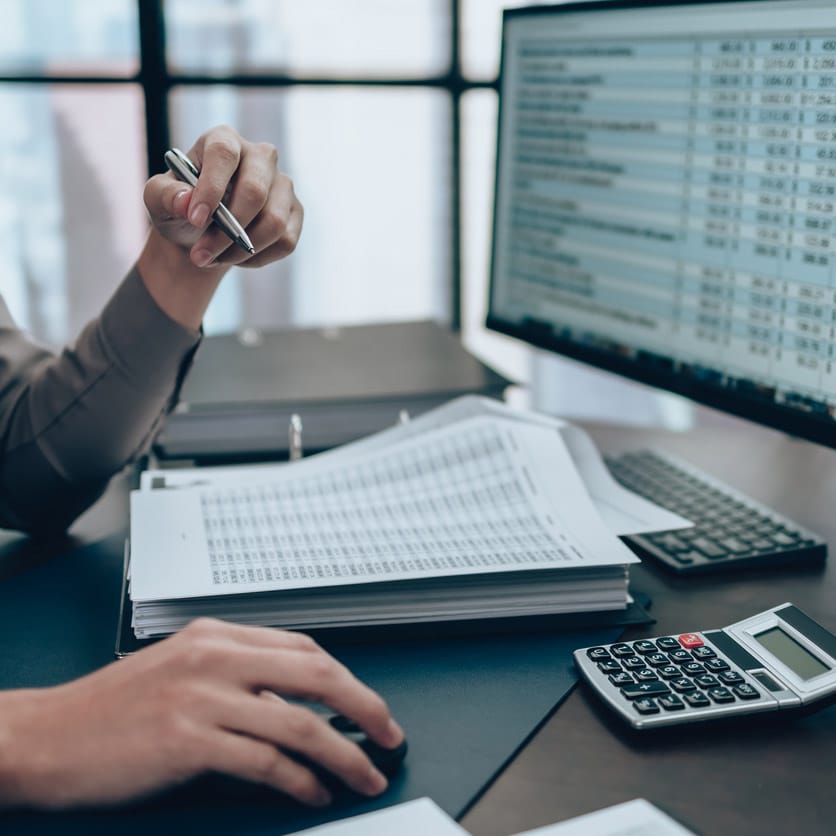 Person working at desk with financial documents for forensic litigation consulting analysis.