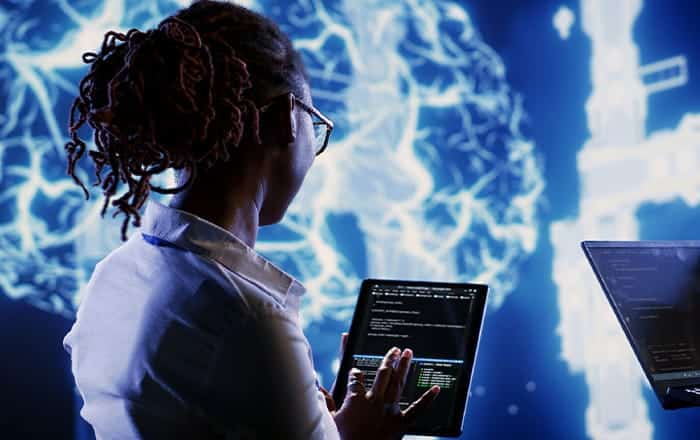 Person using tablet with code, glowing digital brain shows Hospitality Churn Prediction analytics.