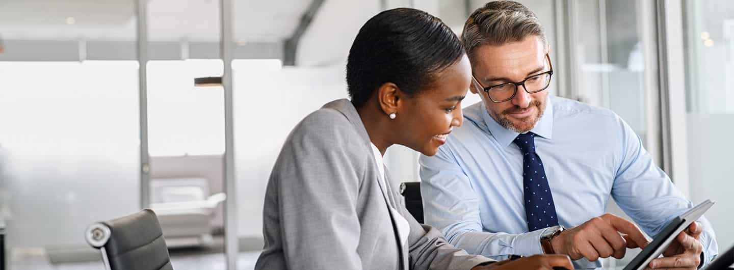 Confident business man in formal clothing working with african american woman showing data on digital tablet.