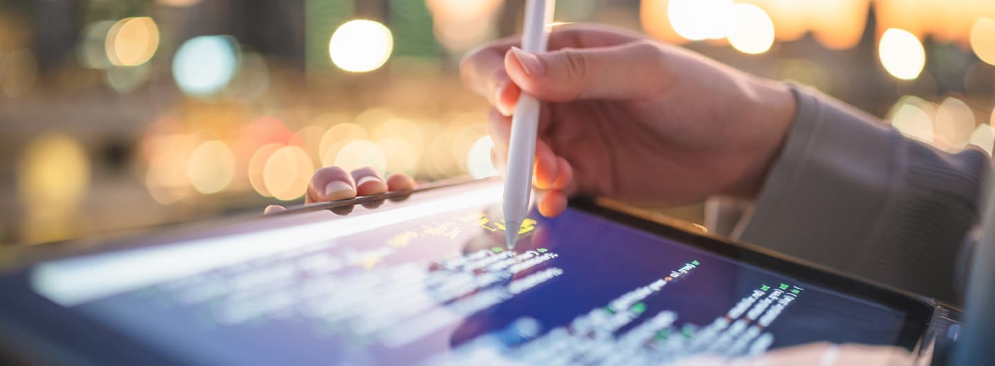 Hand using a stylus to write code on a tablet, showcasing CRE Digital Transformation Consulting.