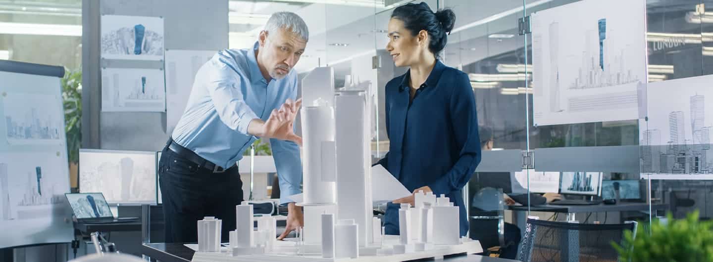 Chief Male Architect and Female Engineer Work with City Buildings Model. Bright People Work as Urban Planners.