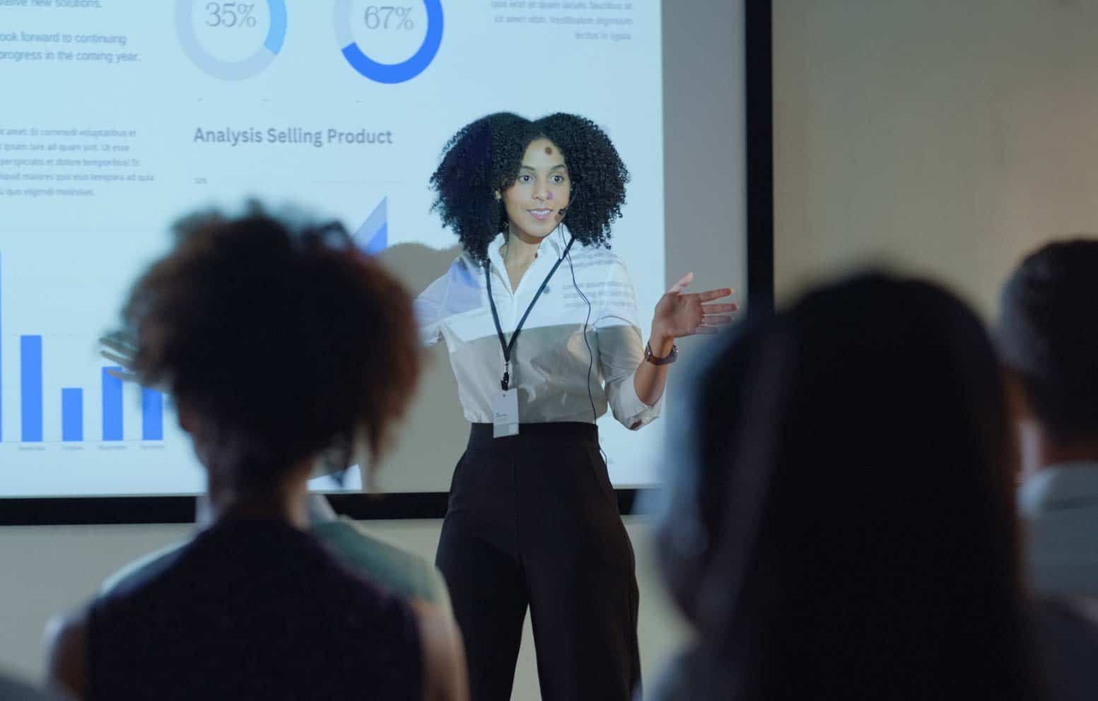 Woman presenting luxury retail corporate performance consulting charts to an engaged audience.