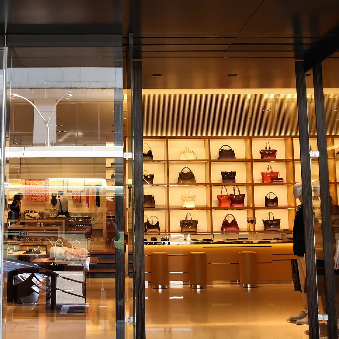 Luxury handbags displayed on shelves inside a brightly lit - Luxury Retail IT Consulting.