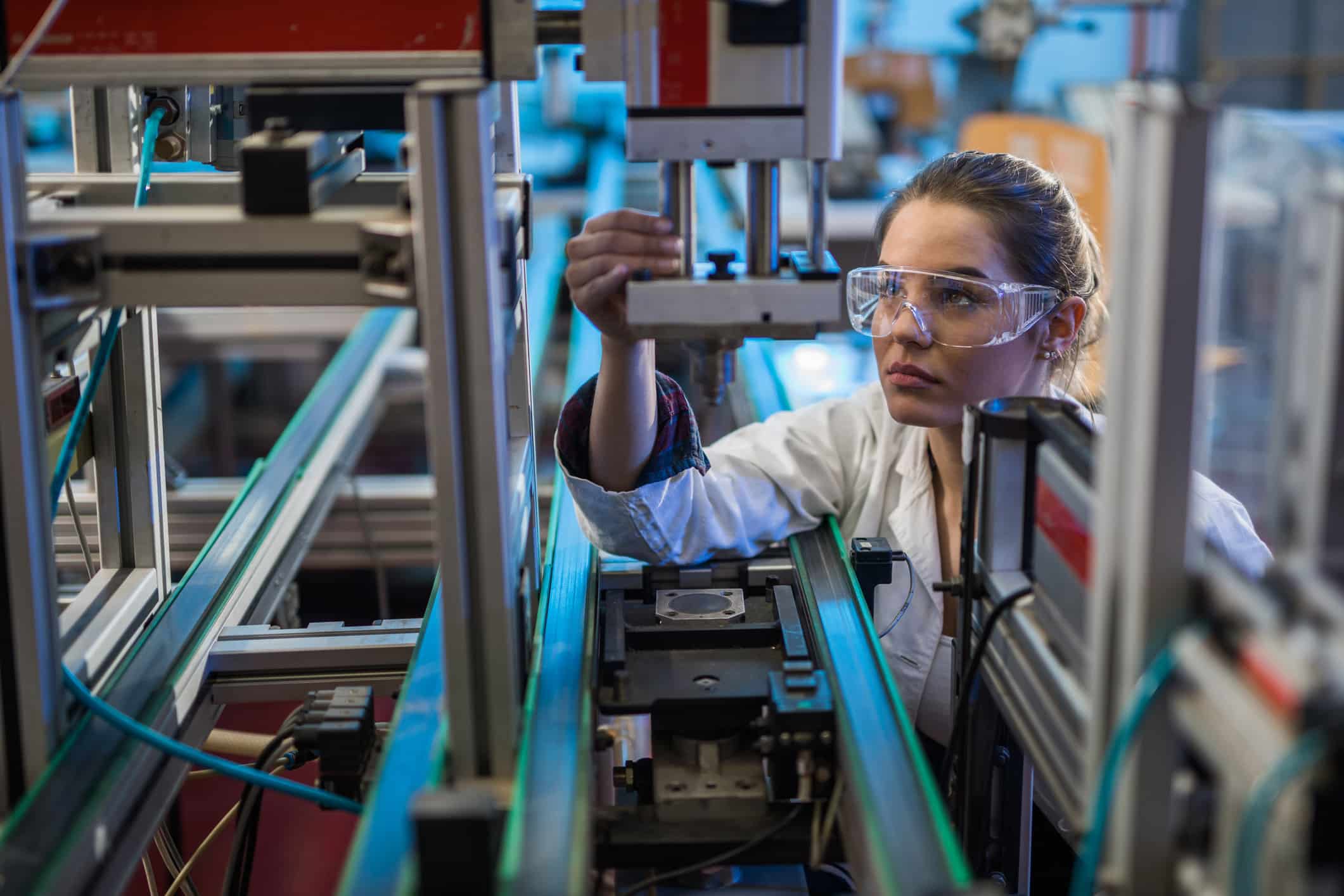Woman in safety glasses operating machinery, showcasing Manufacturing Innovation Strategy Consulting