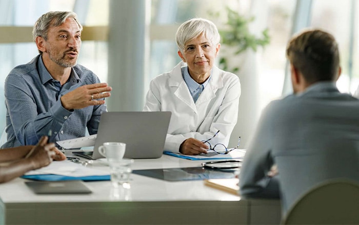 Two professionals discuss Healthcare & Life Science Corporate Performance Consulting in an office.