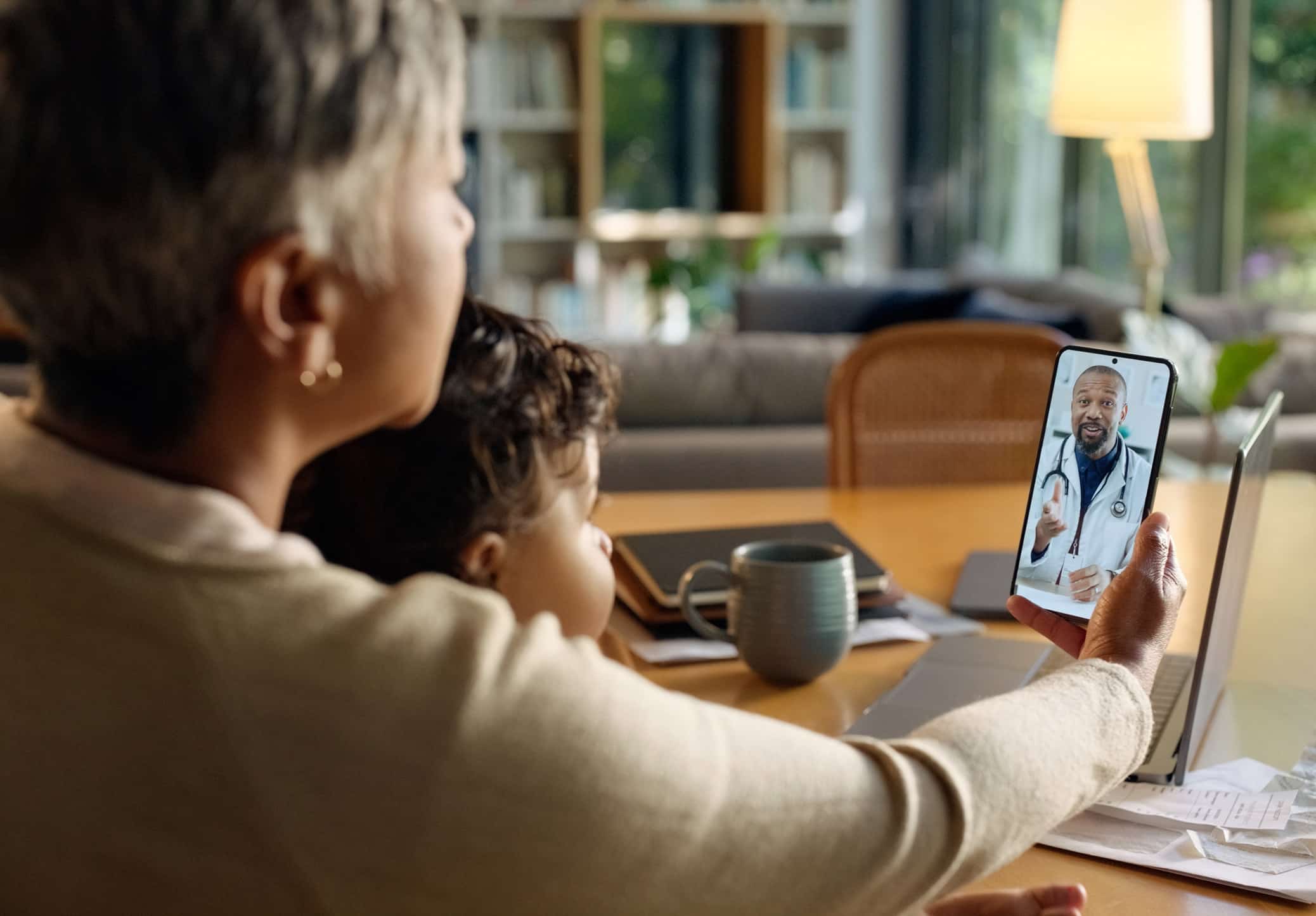 A woman and child join a healthcare digital transformation consult via video call at a desk.