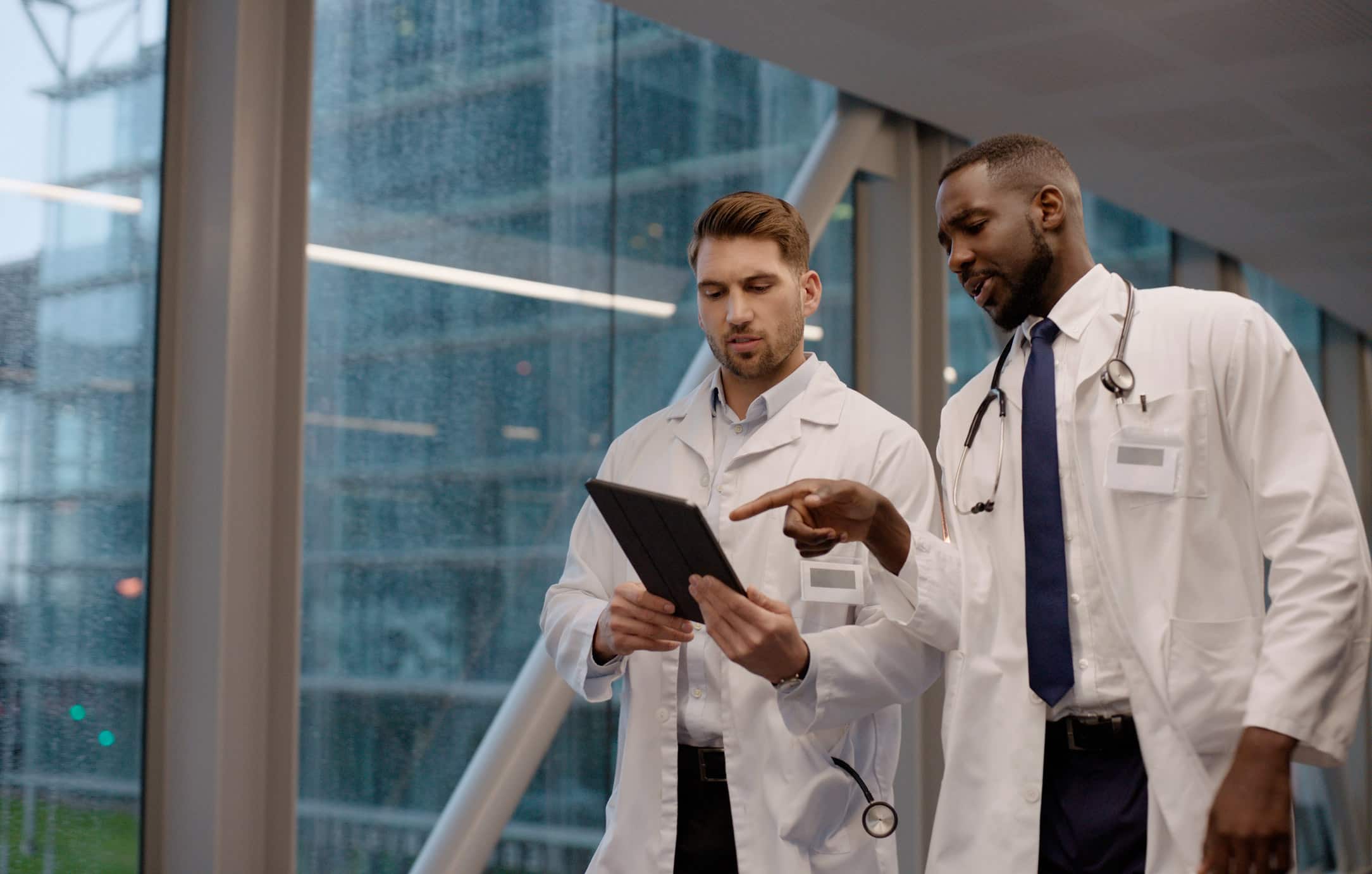 Two doctors discuss data on a tablet, showcasing Healthcare & Life Science IT Consulting.