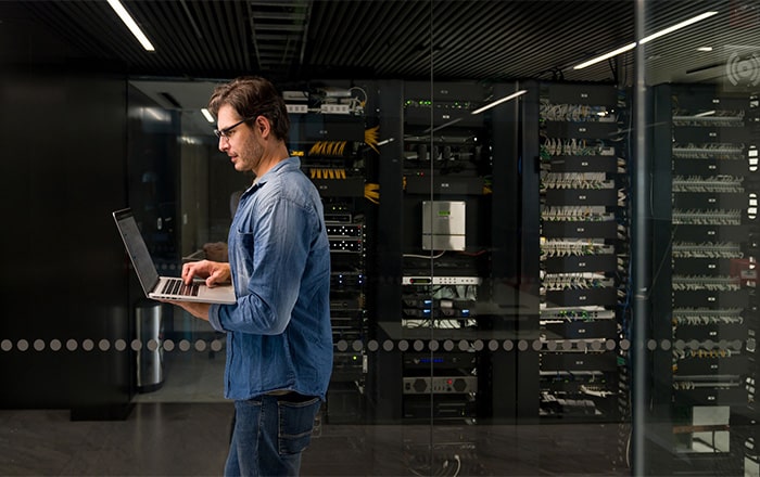 Man using a laptop in a server room, showcasing IT disaster recovery consulting services.
