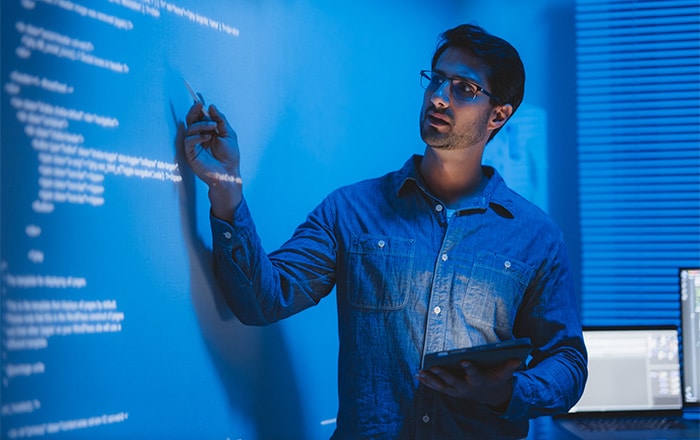 Man in glasses codes on screen, tablet in hand, in mobile device management consulting room.