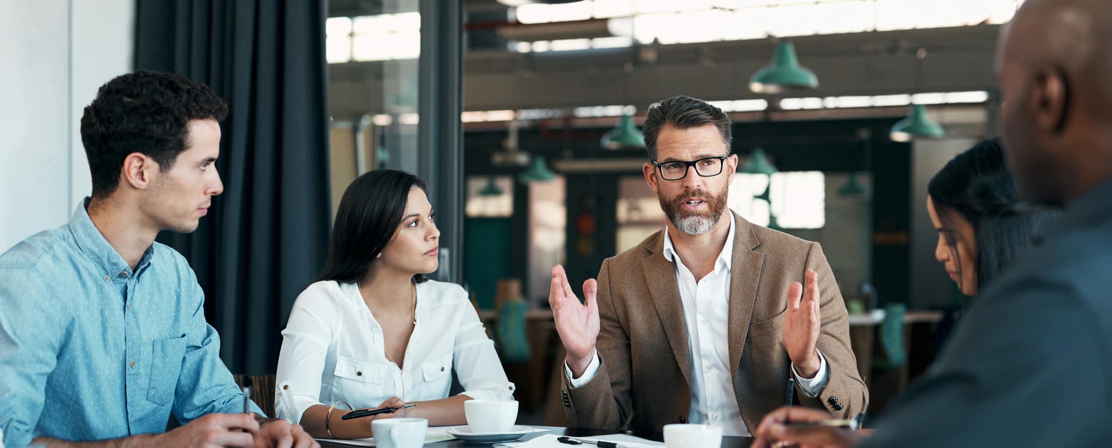 Five people at a table in a business meeting discussing talent acquisition consulting.