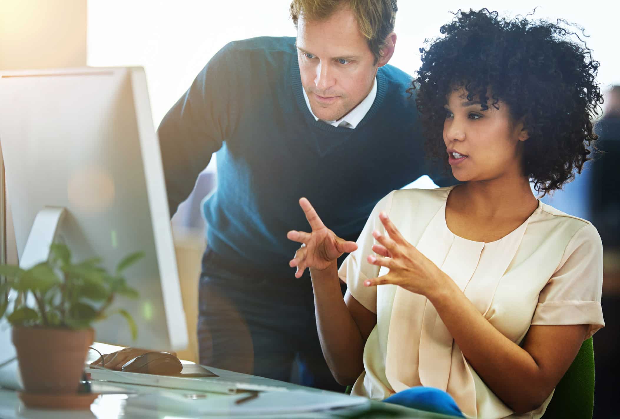 Two colleagues discuss Law Firm Role Realignment while looking at a computer screen in an office.