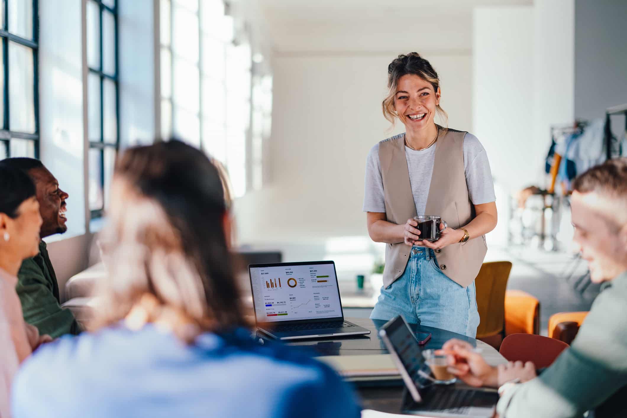 Smiling woman presents Advanced Analytics & Visual Data Exploration to colleagues in bright office.