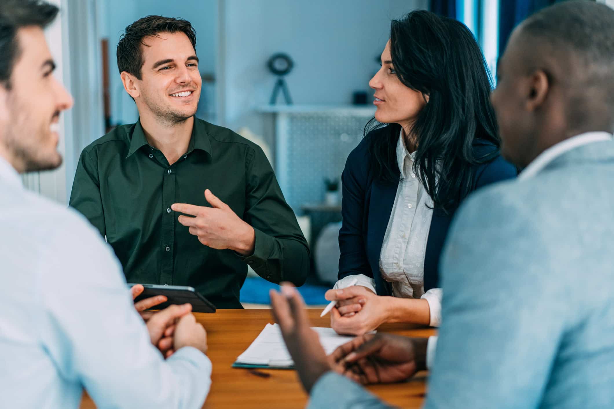 Four people sit around a table, smiling and engaged in change leadership and alignment discussions.