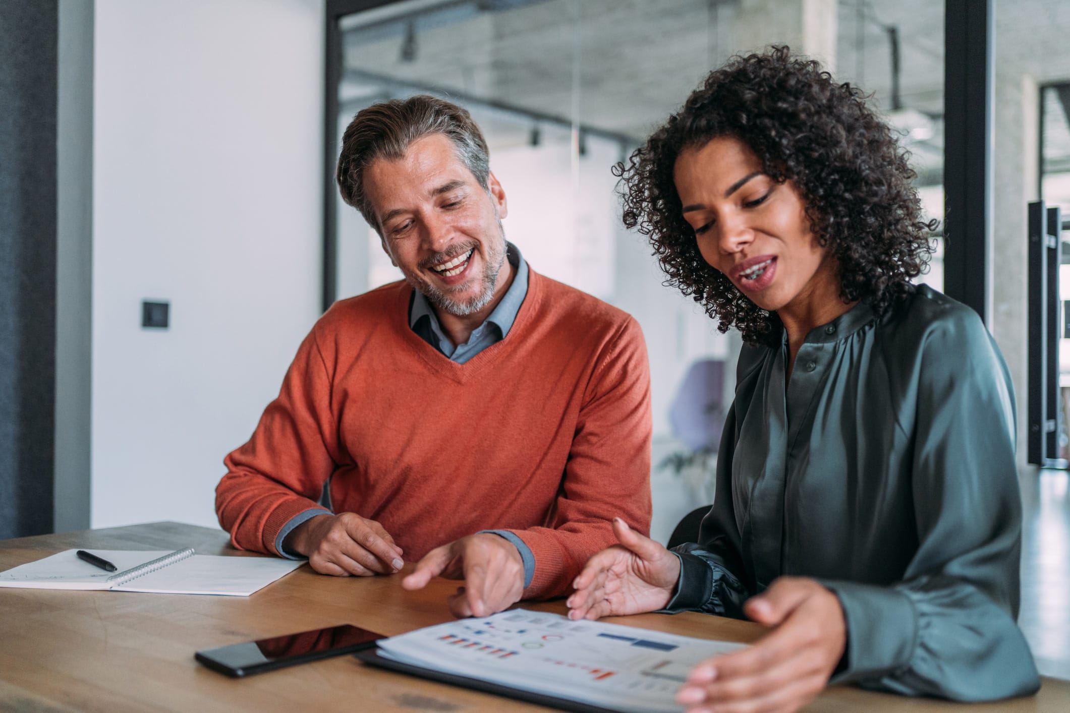 Two colleagues discuss client lifecycle mapping at a desk in a modern office setting.