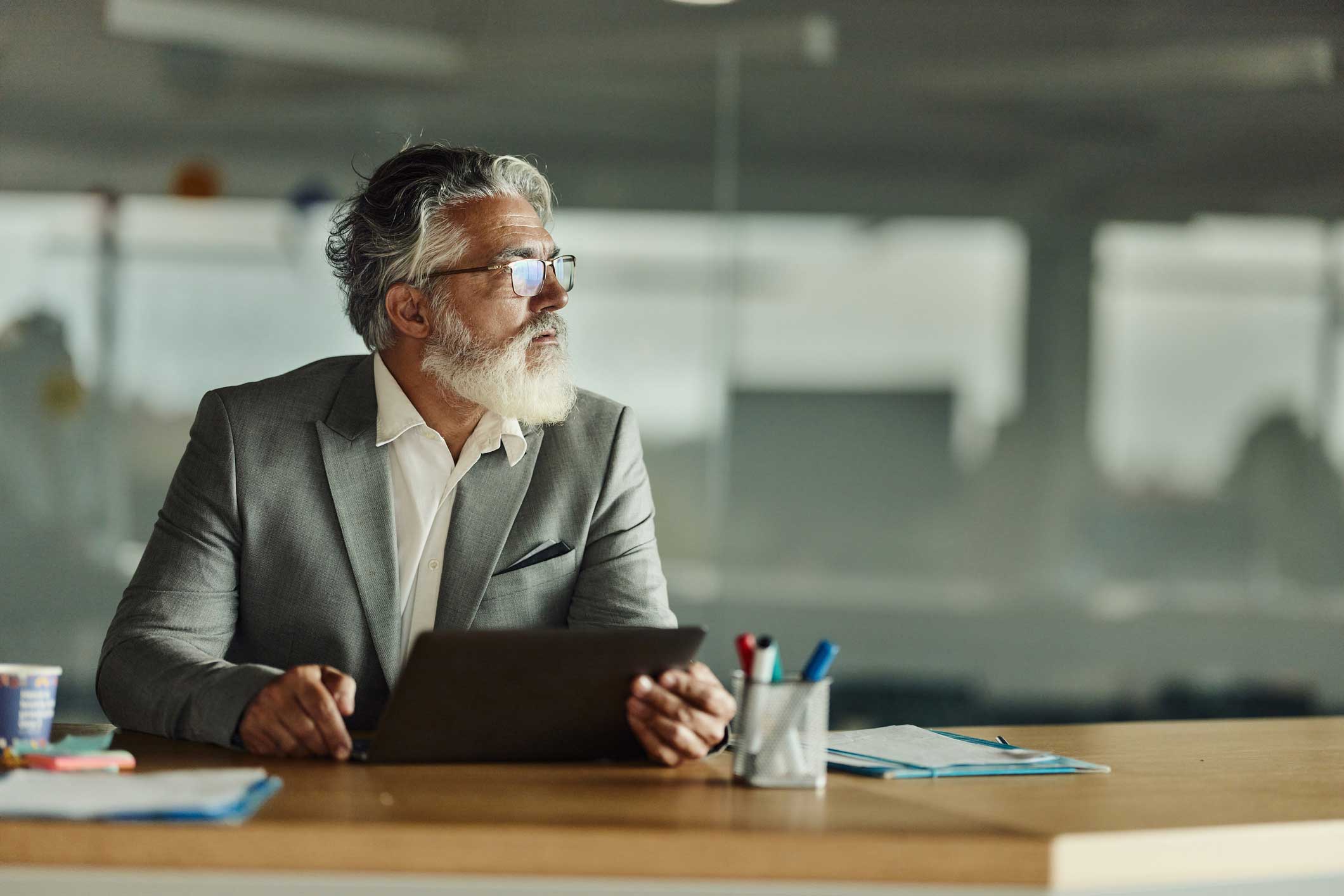 Older man in a gray suit at his desk, representing an email security consulting firm.