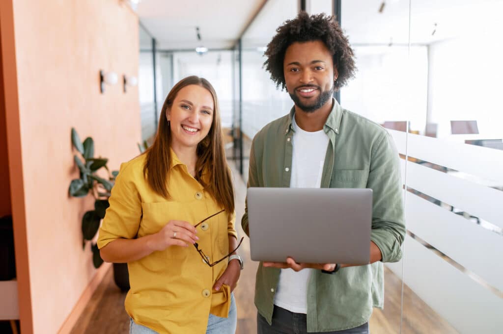 Two people smiling in an office, discussing employee benefits communication.