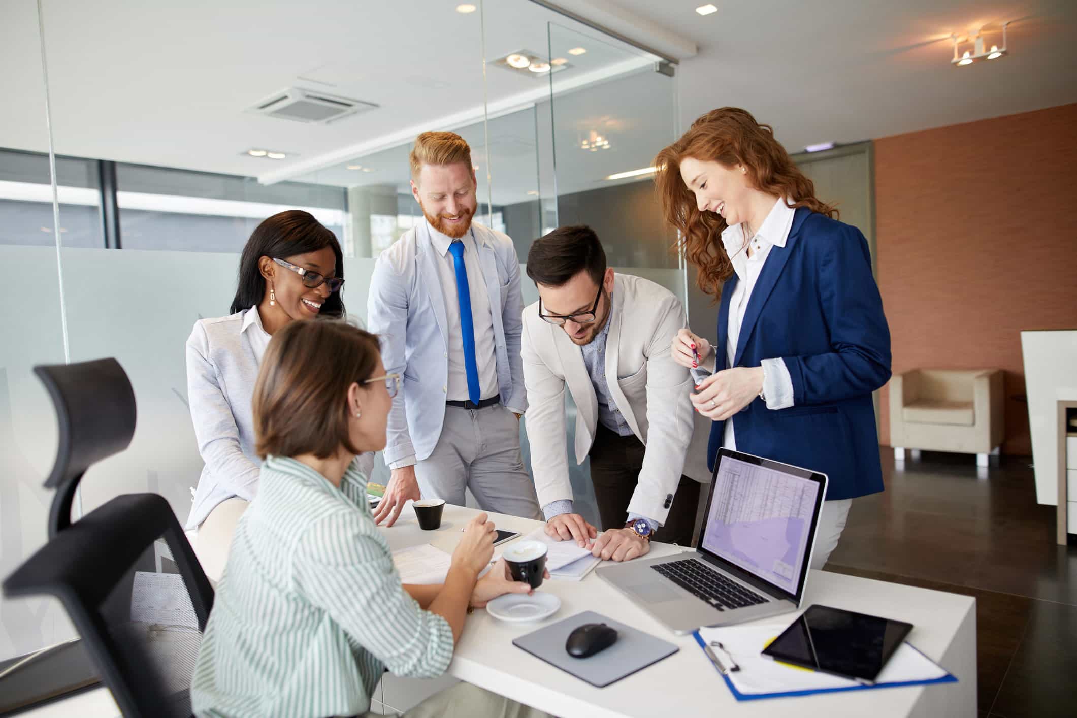 Five colleagues discuss change management engagement around a desk in a modern office.