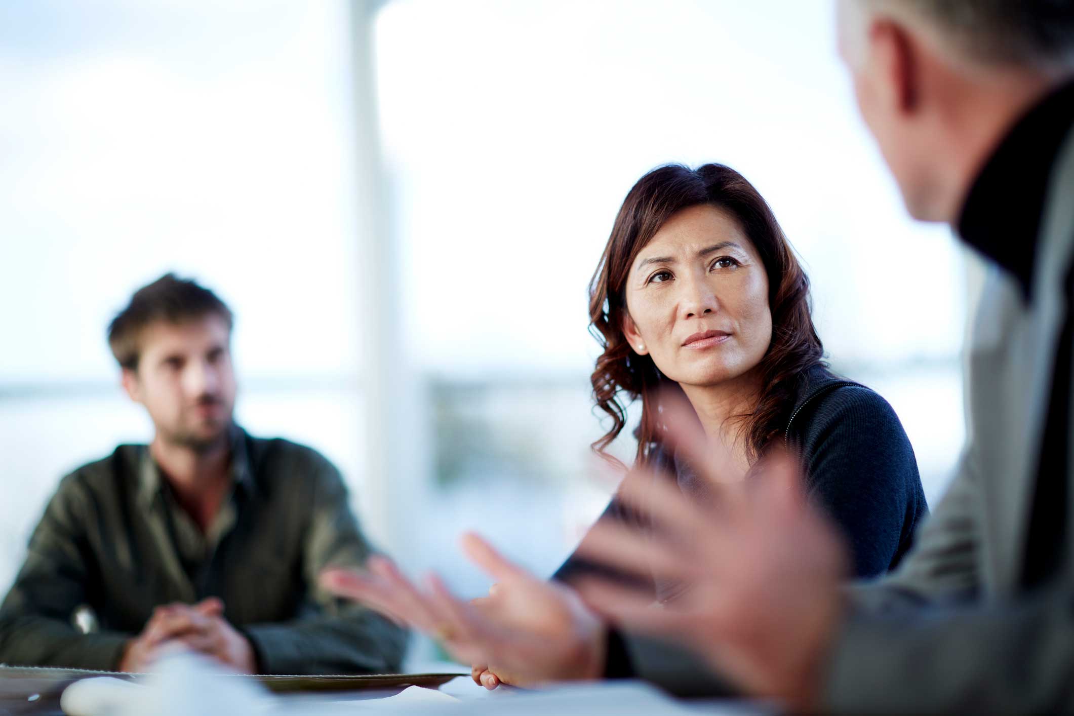 Three people in a law firm expense management meeting, with a woman listening intently.