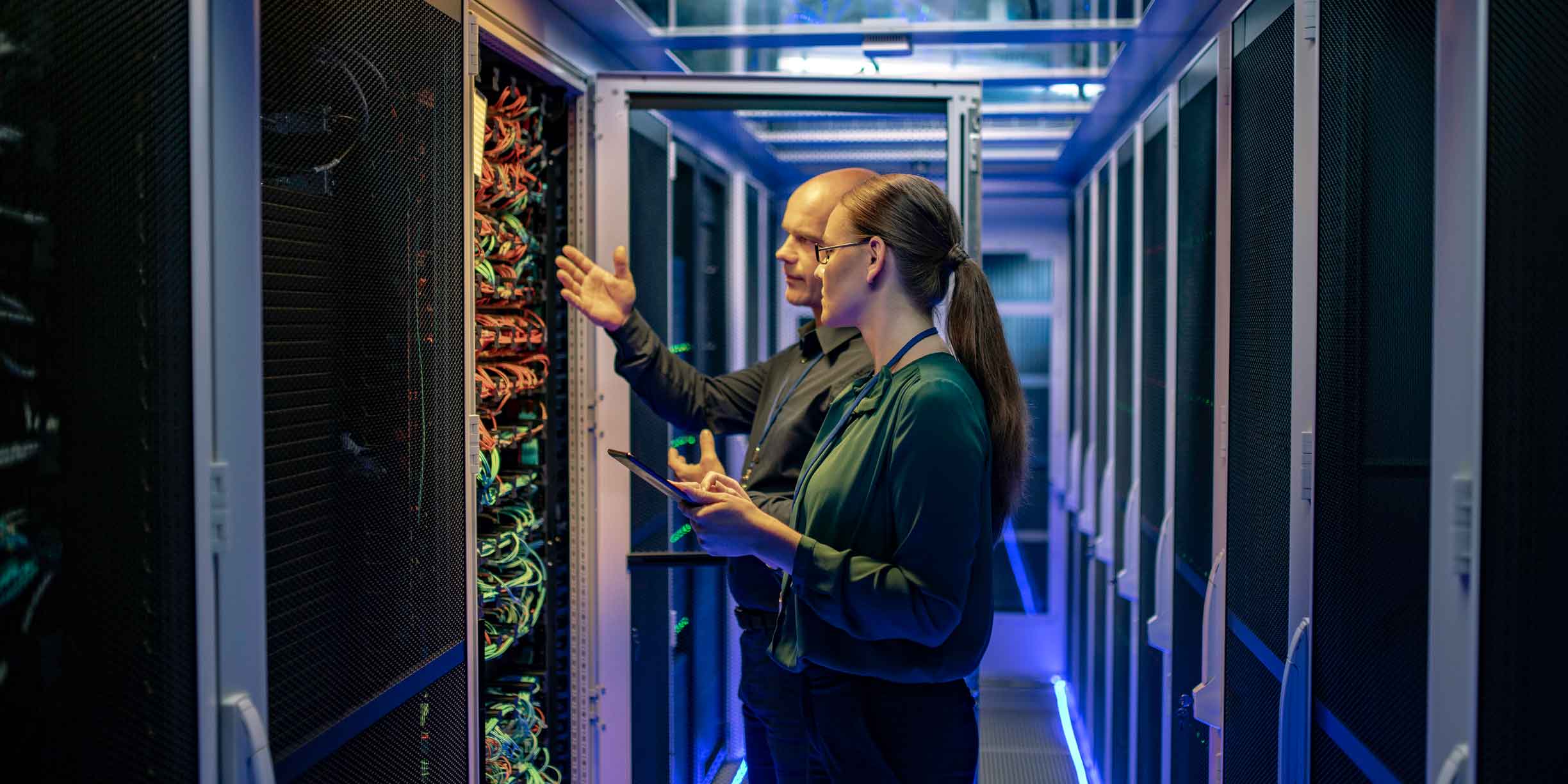 Two people inspecting servers in a data center focused on continuous improvement and testing.