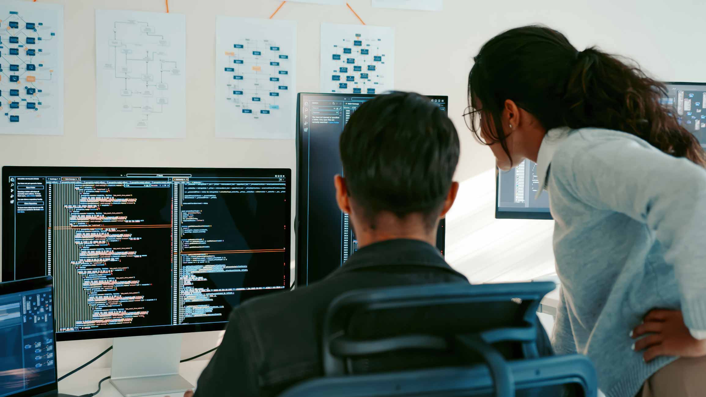 Two people review code and technical diagrams while discussing incident response strategies.