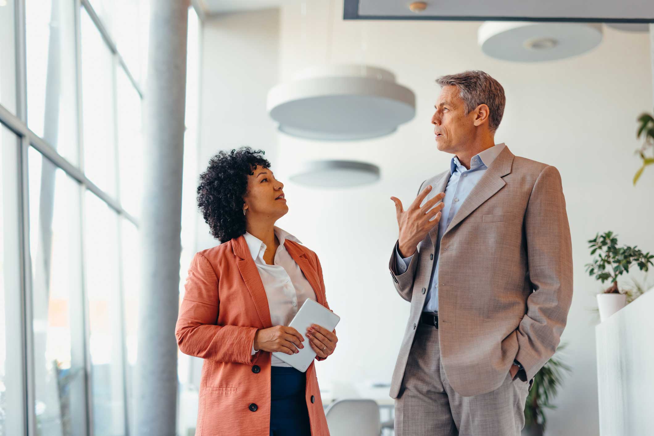 Two business professionals discuss with cybersecurity compliance consultants in a modern office.