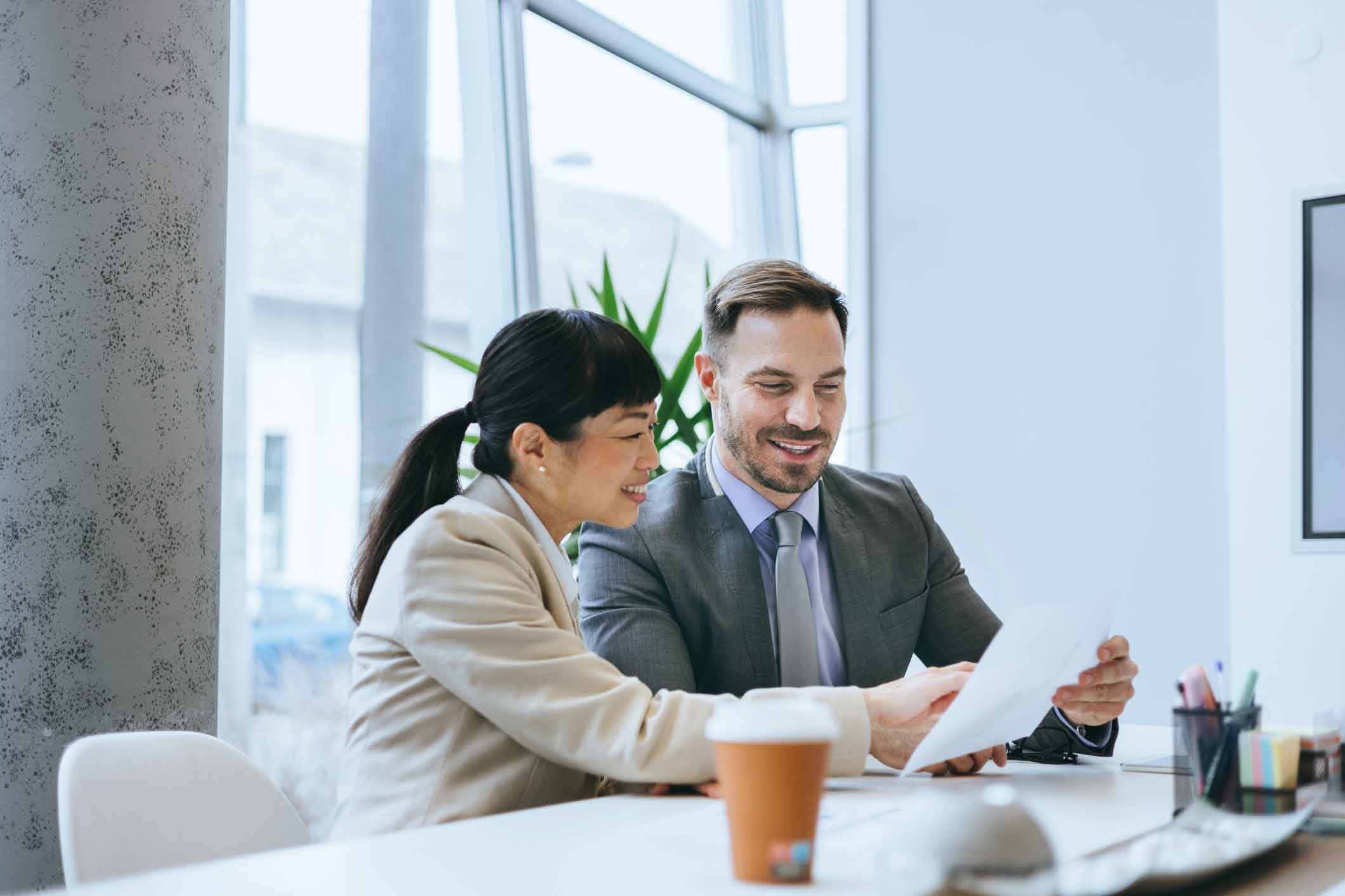 Two businesspeople smiling as they review a cybersecurity compliance Framework document together.