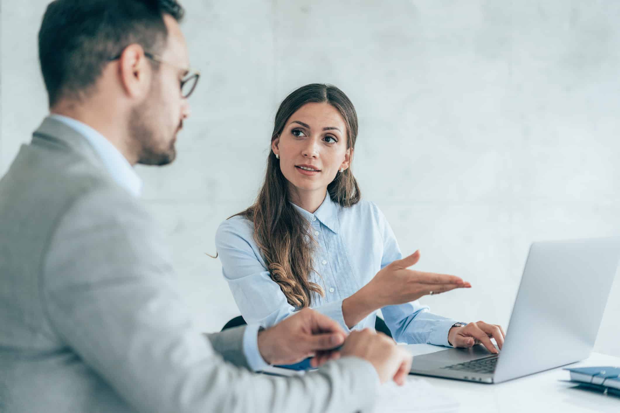 Two colleagues discuss Big Data Strategy Consulting at a desk in a modern office setting.