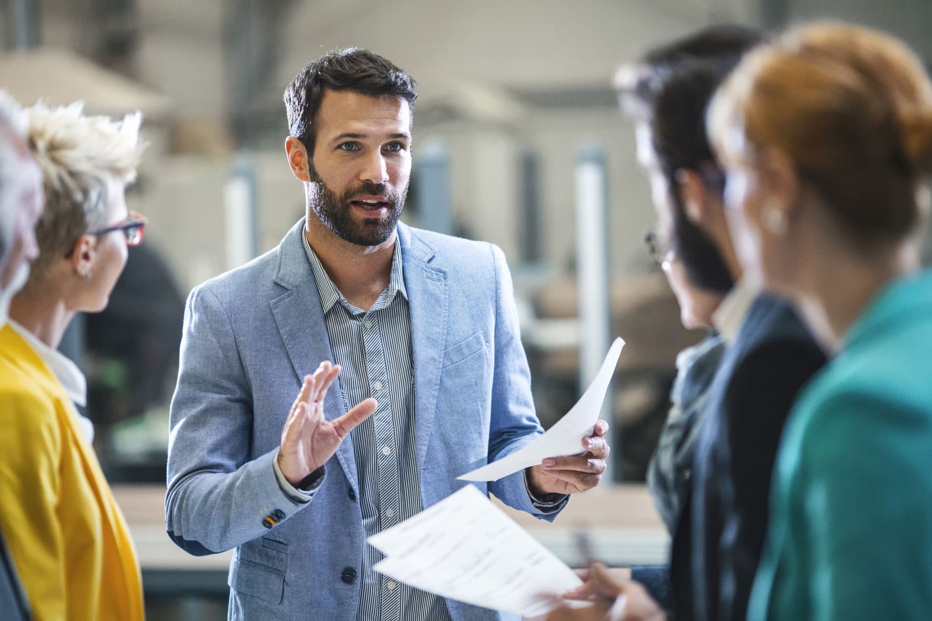 Man in a light blue blazer discusses Big Data Strategy Realization with colleagues in an office.