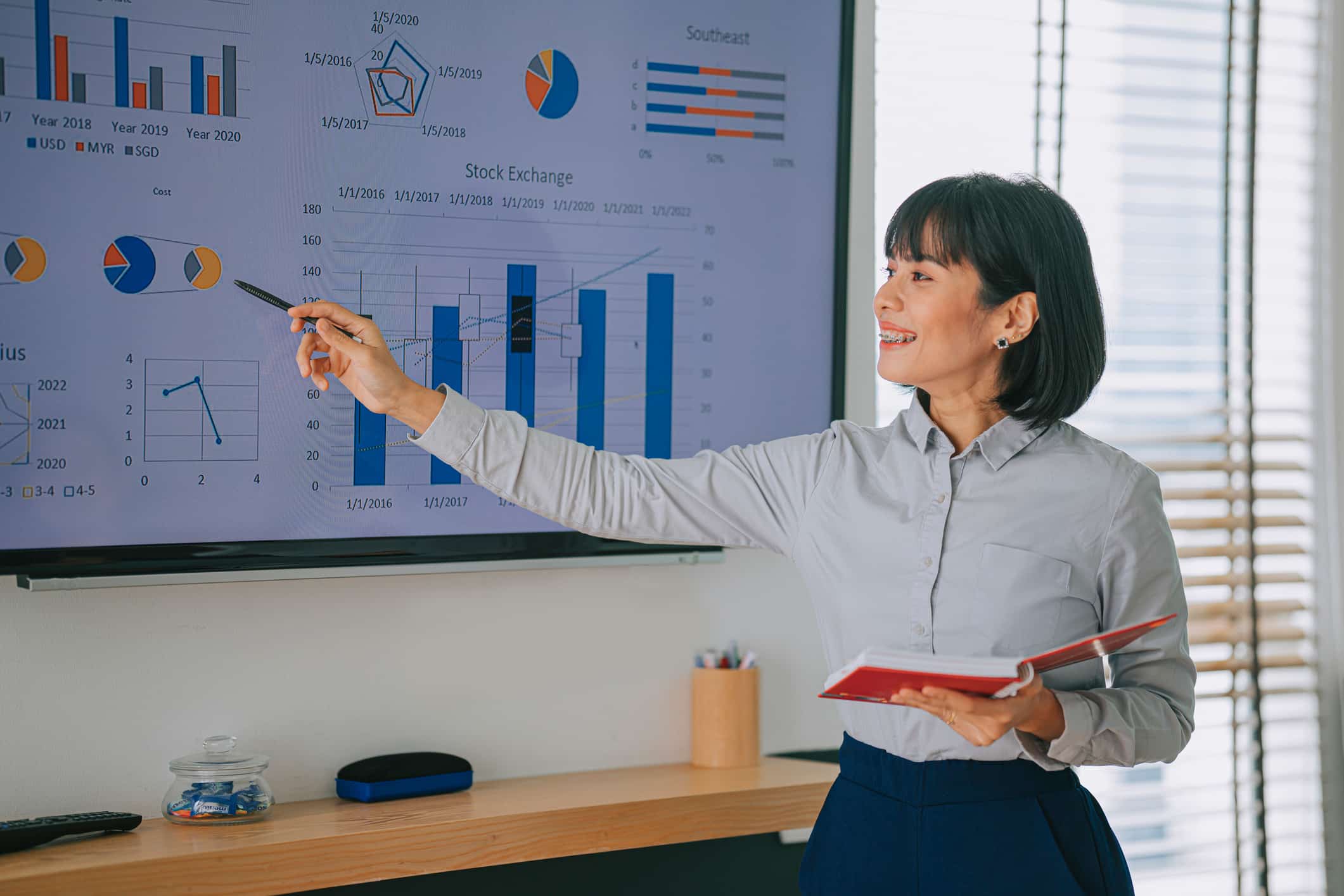 Woman presenting data charts on a screen, highlighting Data Strategy & Predictive Analytics.