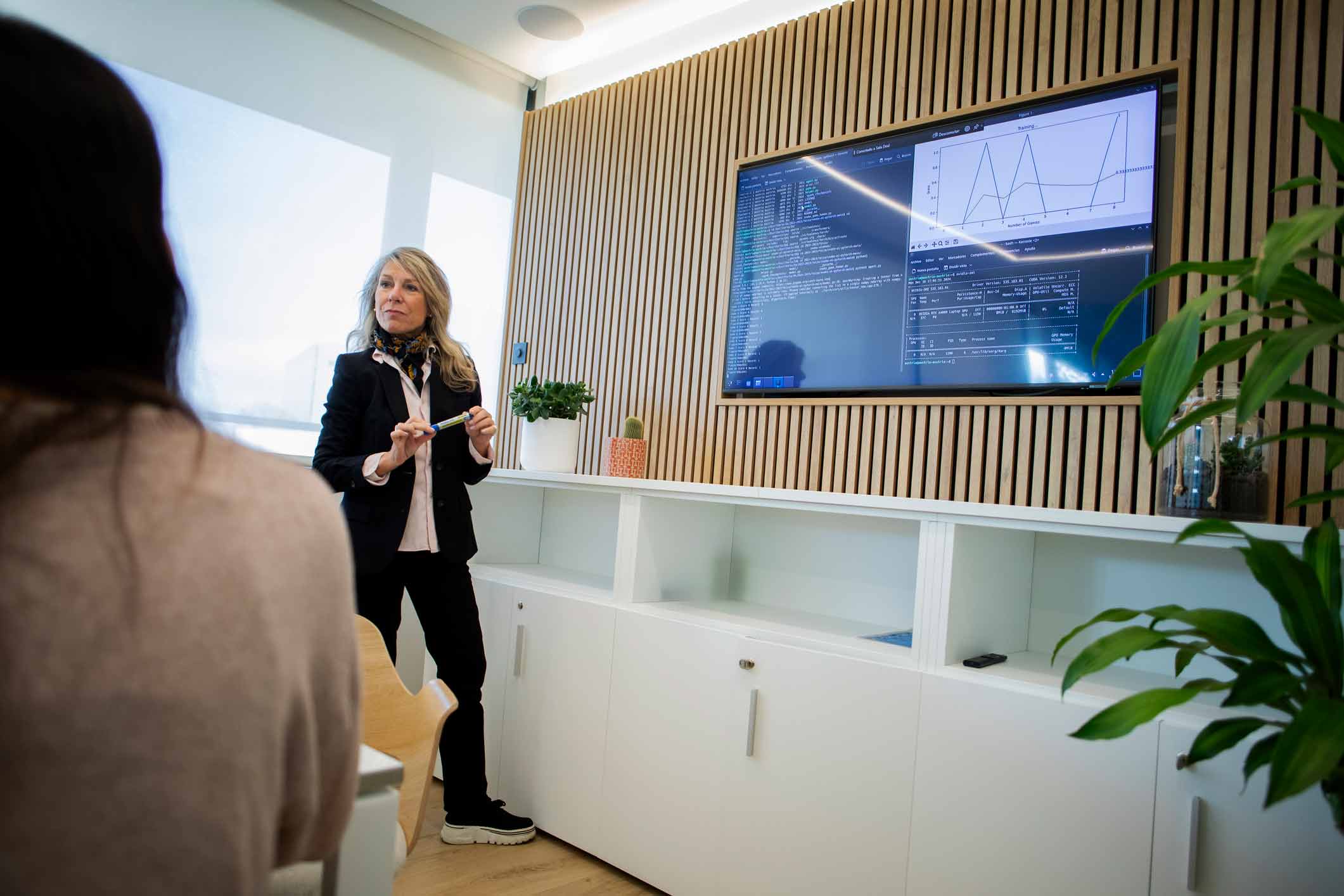 Woman presenting data and charts on Machine Learning Readiness to a seated audience in an office.
