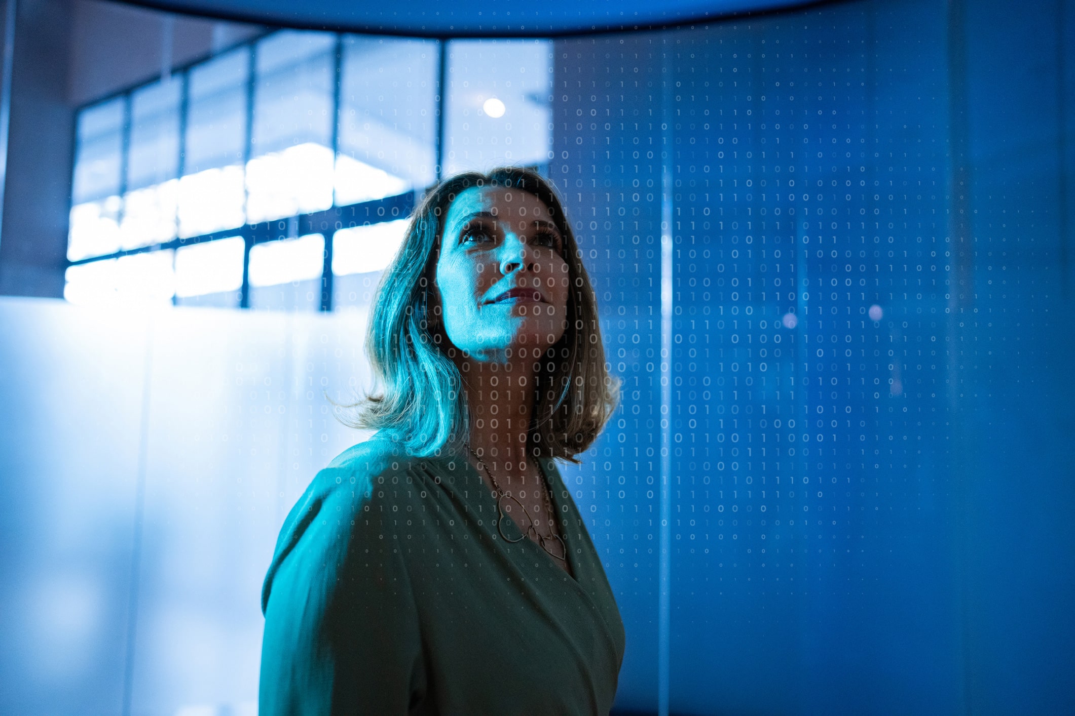 Woman looking up, surrounded by binary code and blue light in an eDiscovery consulting firm.