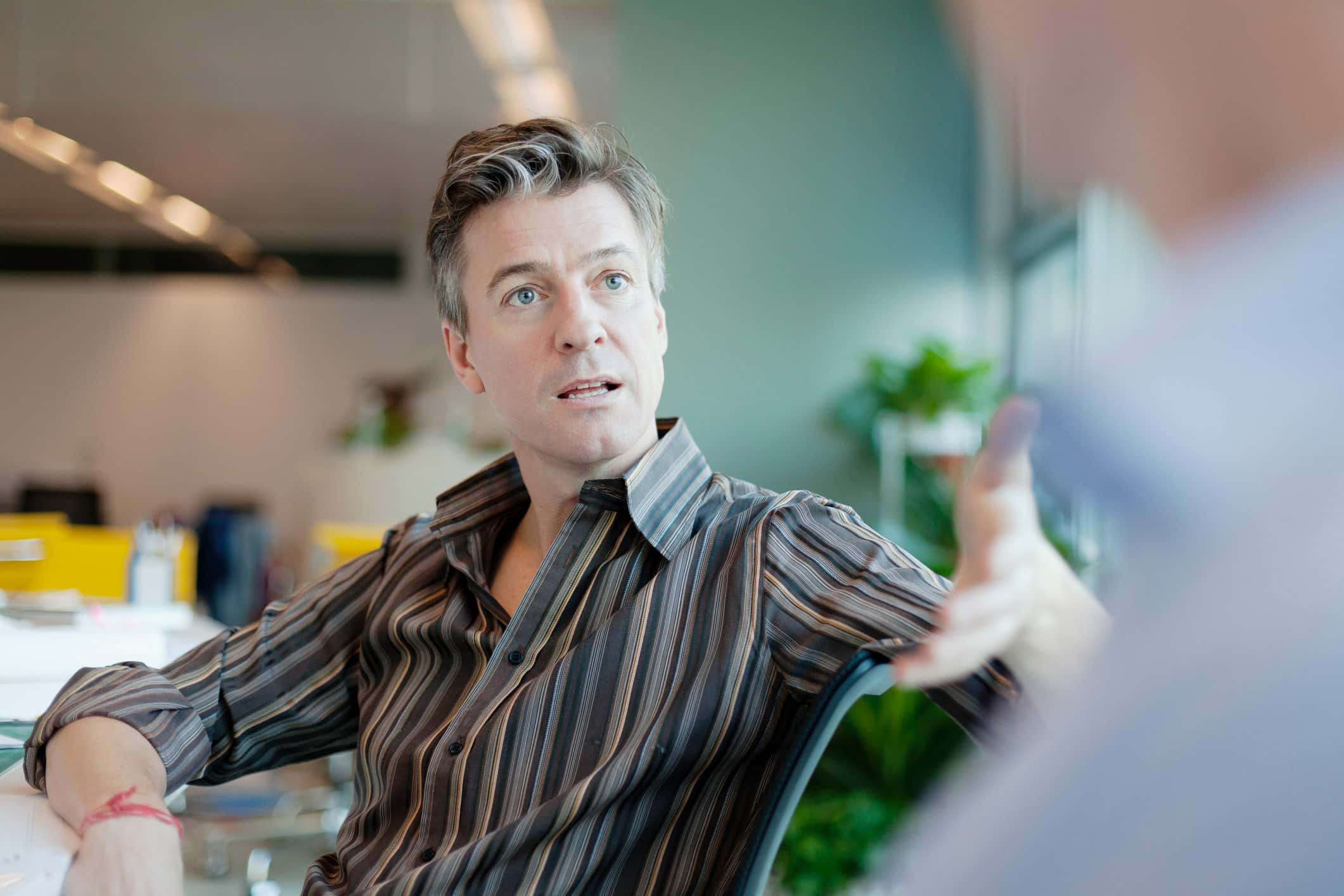 Man in striped shirt discussing with colleague at Securities Litigation Consultants office.