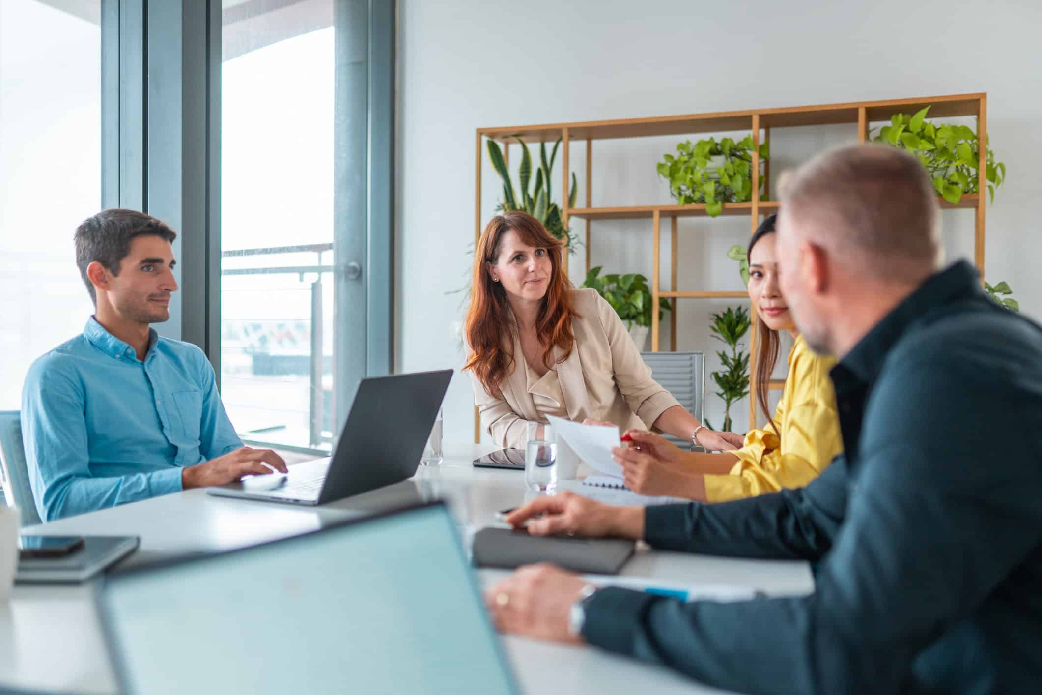 Four people meet around a table at an employee wellness consulting firm’s modern office.