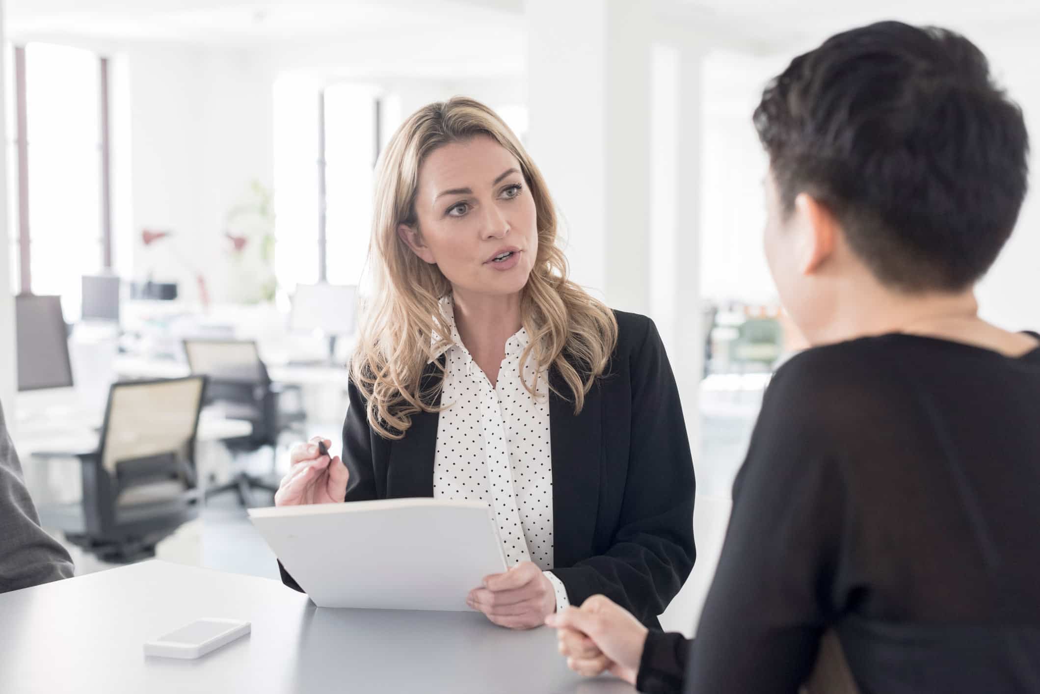 Two people consulting at a desk in a bright, modern office with Business Valuation Consultants.