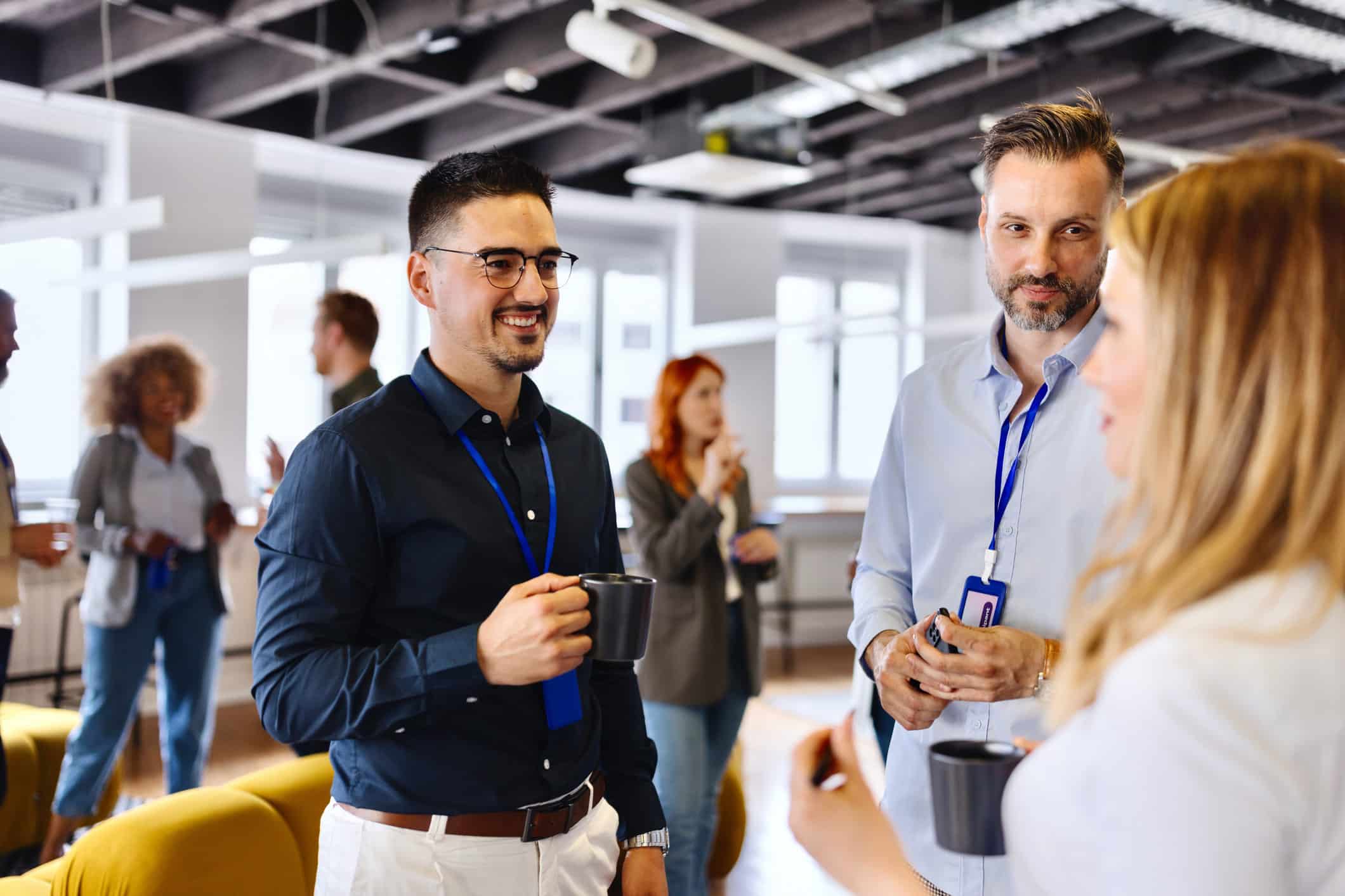 People chatting and drinking coffee at an employee wellness consulting event.