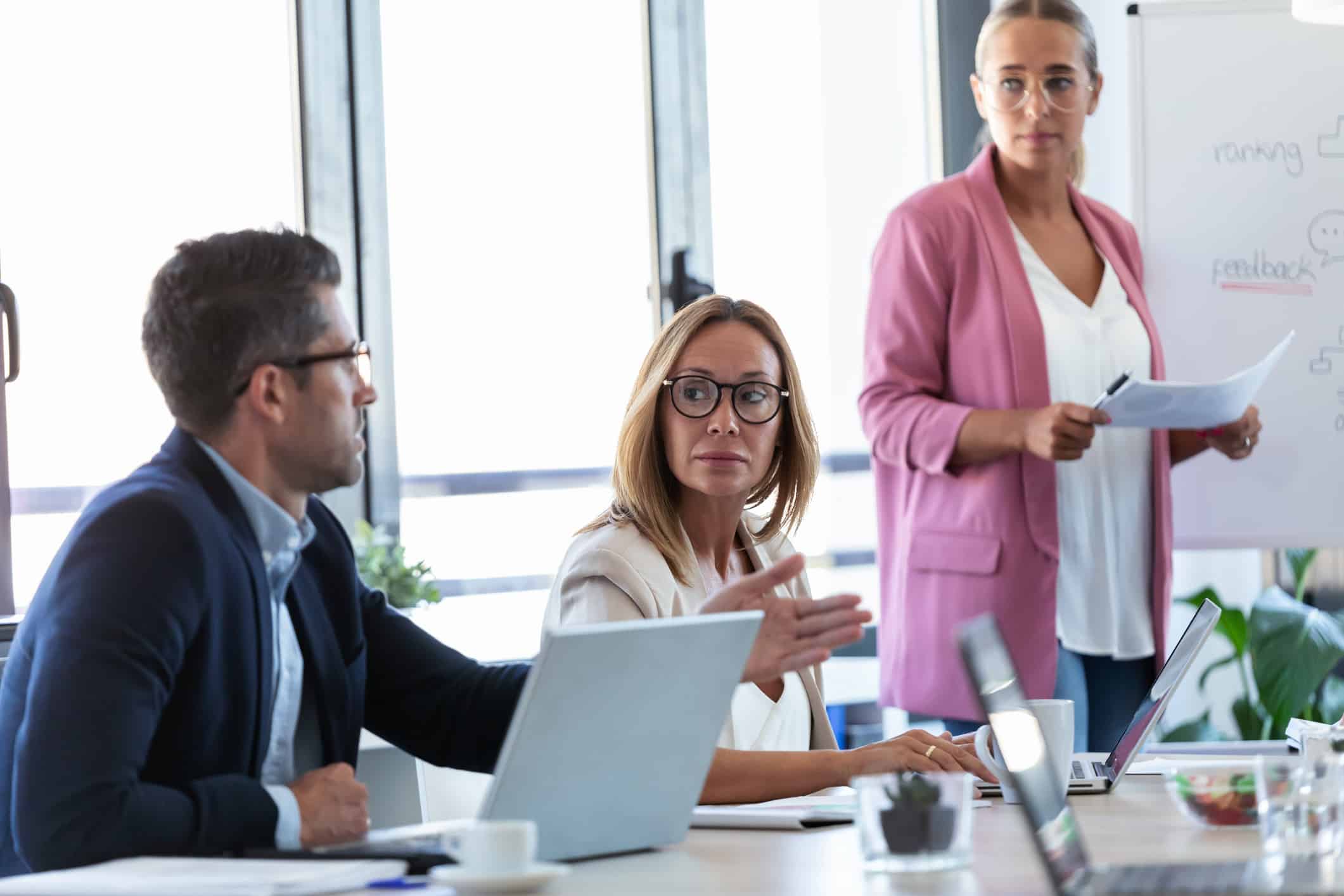 Three colleagues in a meeting discuss Legal Natural Language Processing at a whiteboard.