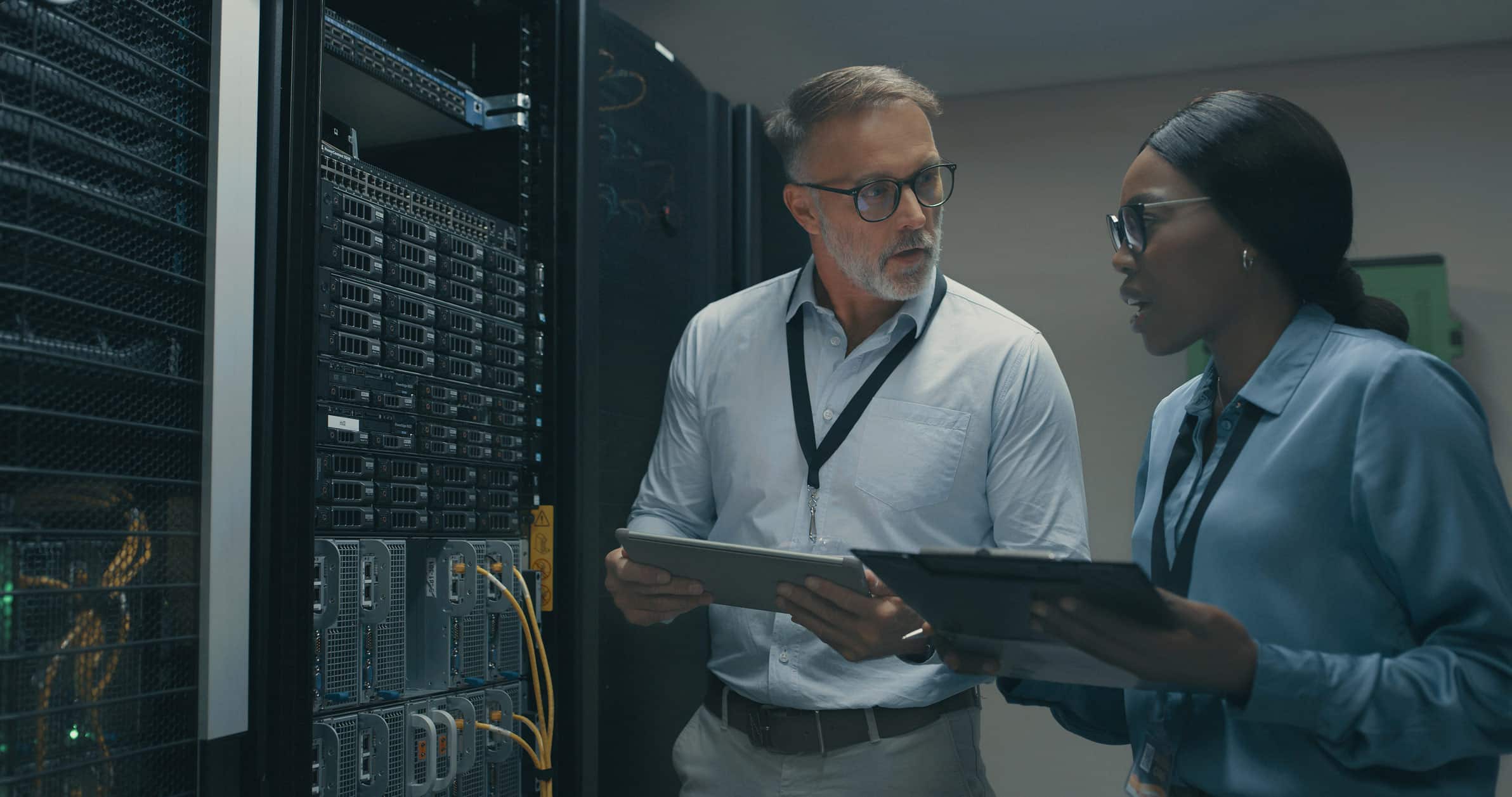 Two IT professionals discuss Modern Data Architecture Advisory while holding tablets in a room.