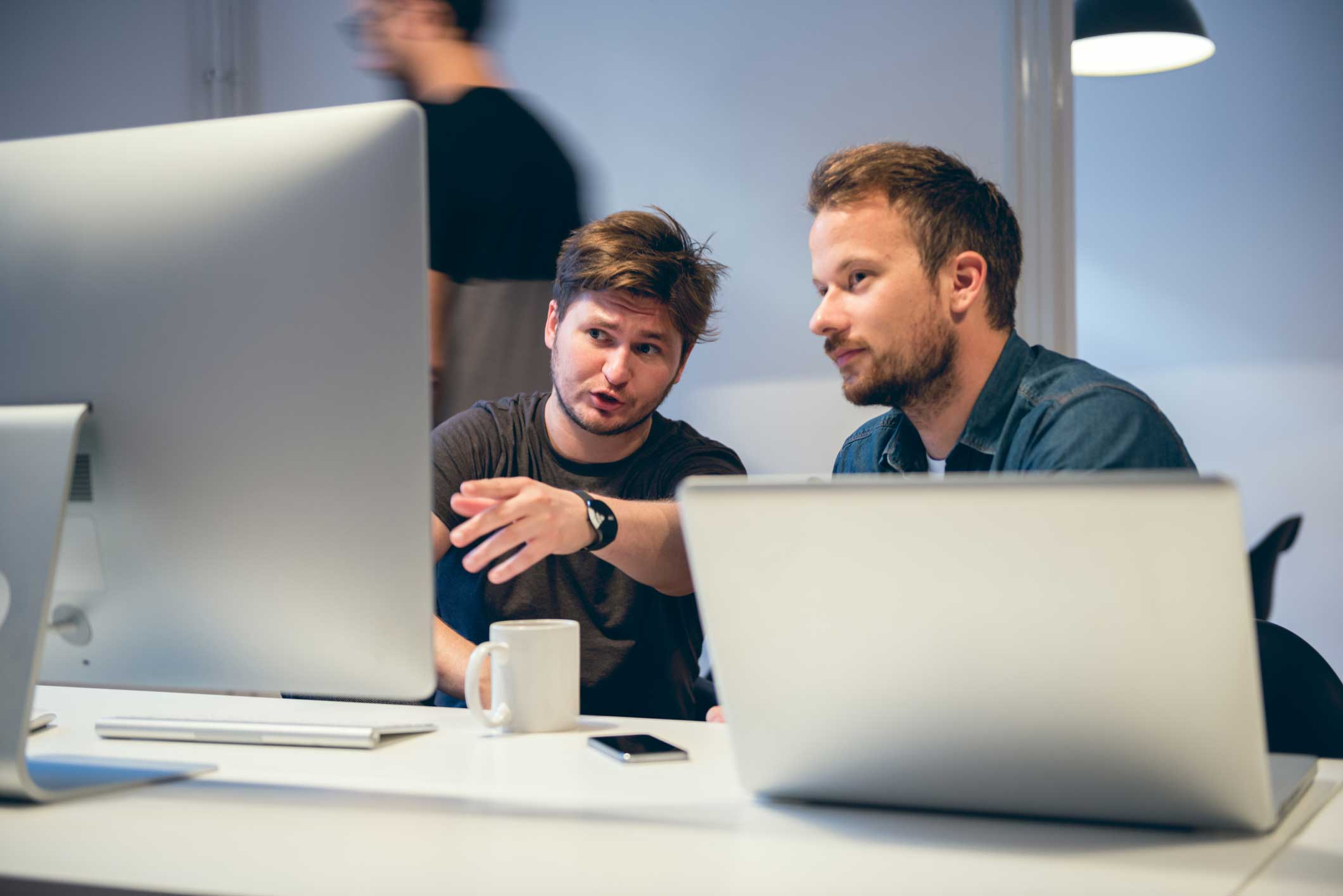 Two men at a desk discussing MDM Execution while looking at a computer monitor.
