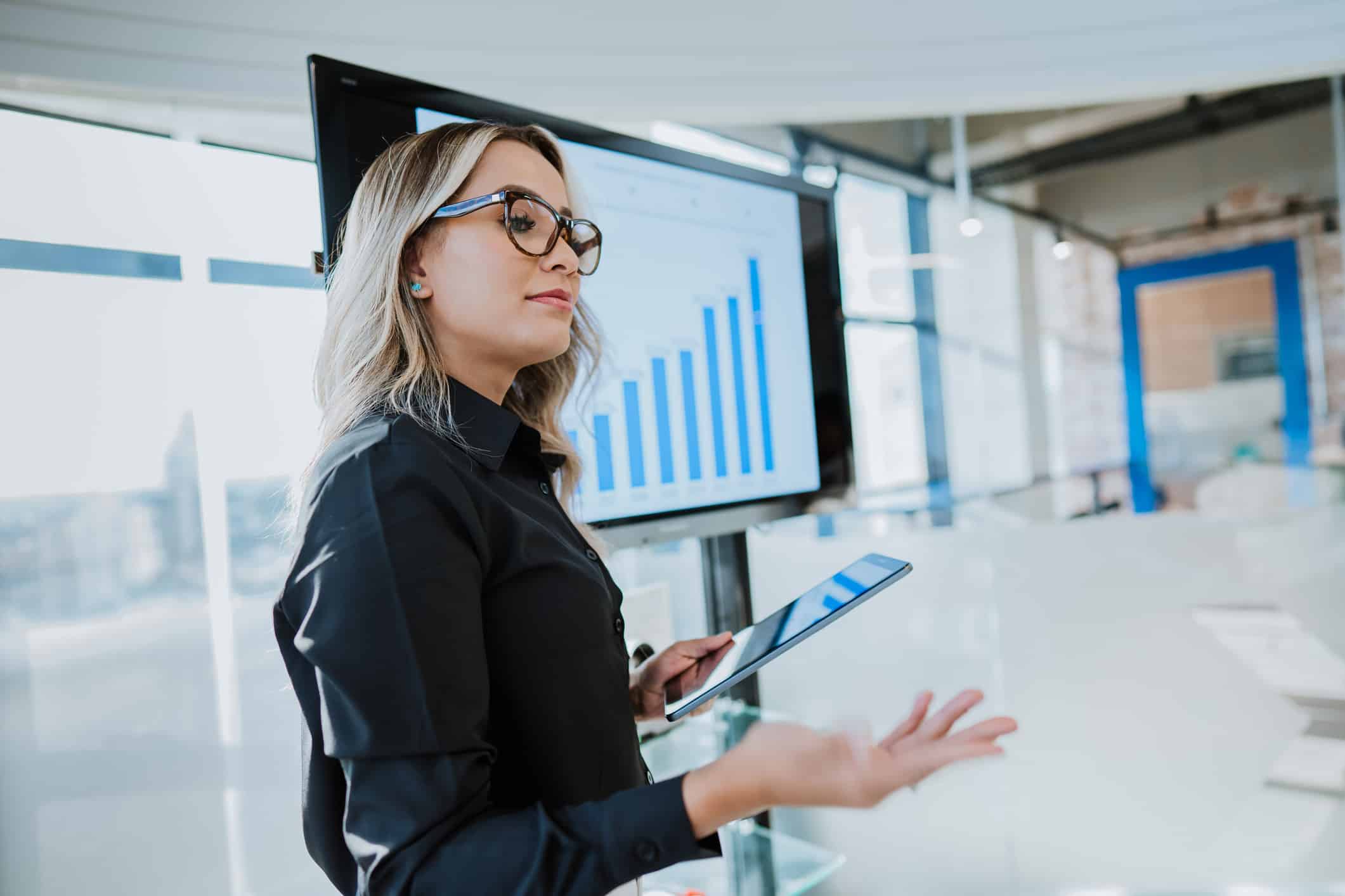 Woman presenting data on AI Execution management with a bar graph displayed behind her.