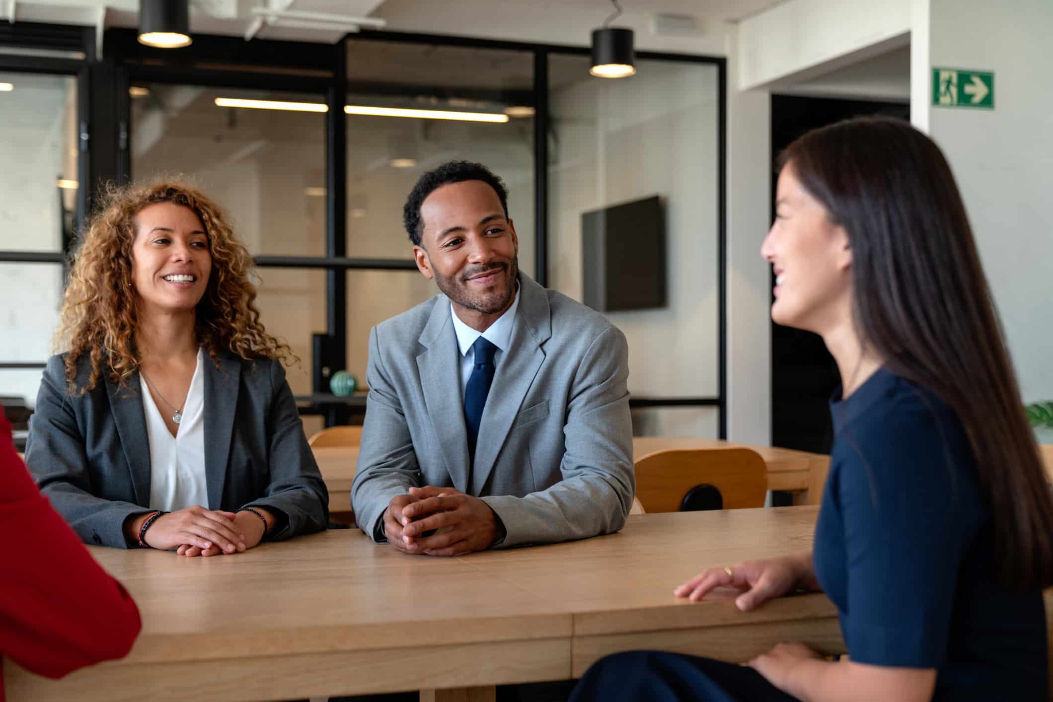 Three people in business attire smile while discussing workforce development execution.