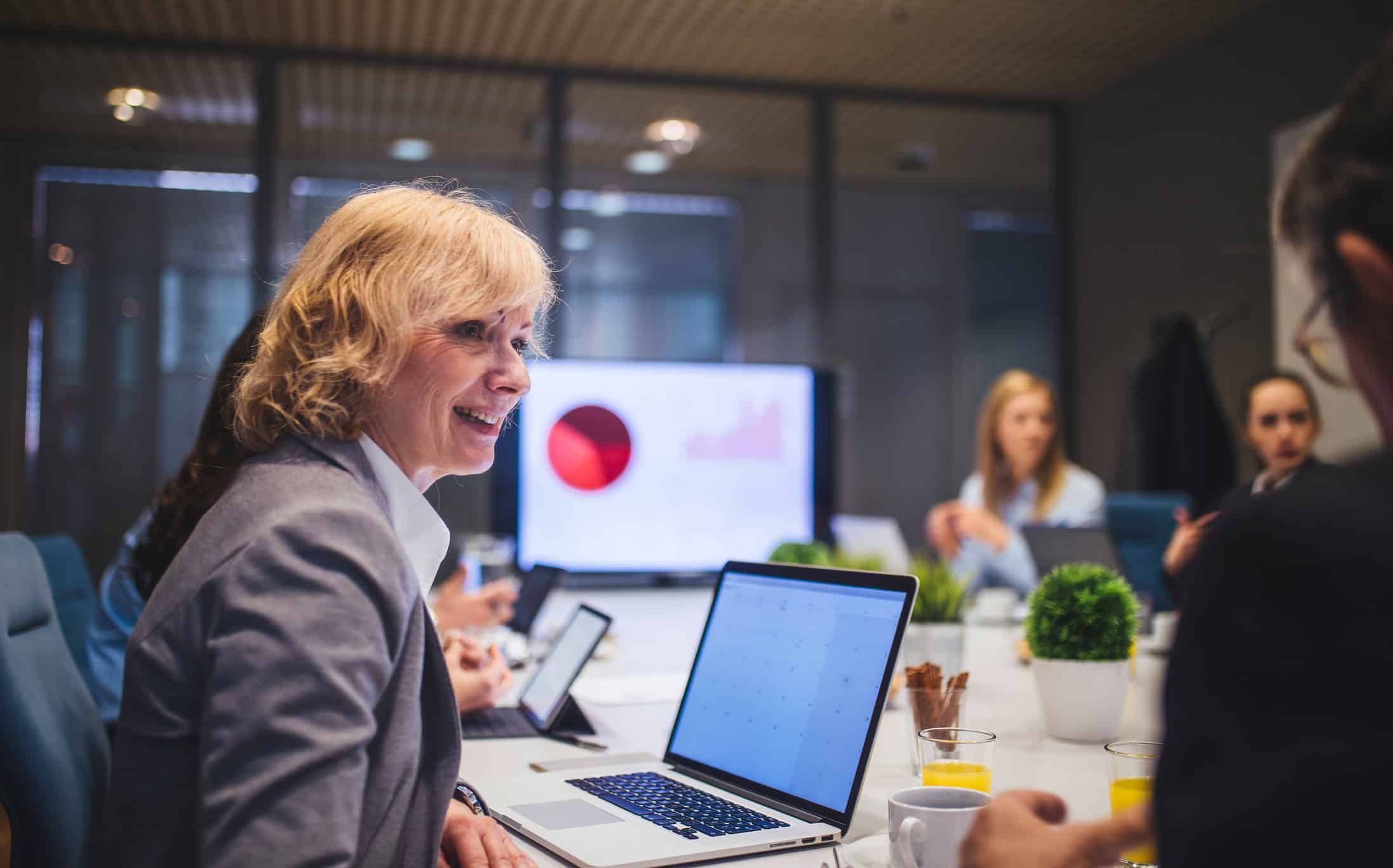 Smiling woman at a business meeting, highlighting employee wellness execution with her team.
