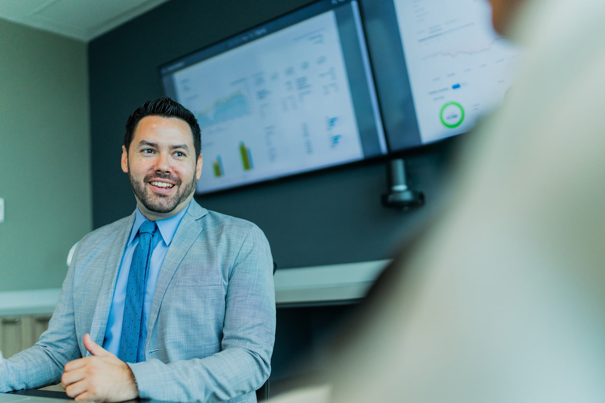Man in a suit smiling during a meeting, discussing Competitive Strategy Execution.